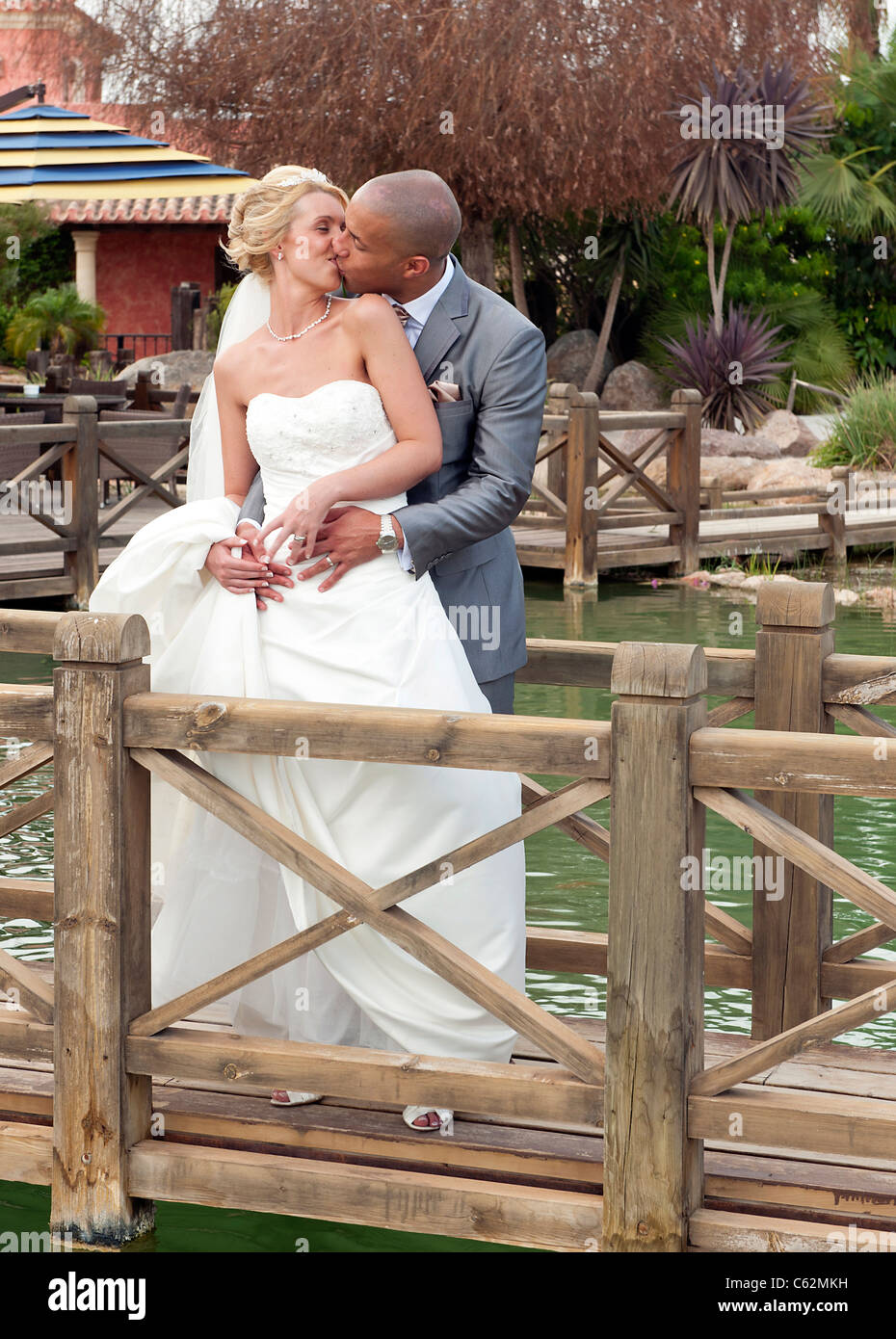 Jeunes mariés appréciant un moment ensemble sur un pont en bois Banque D'Images