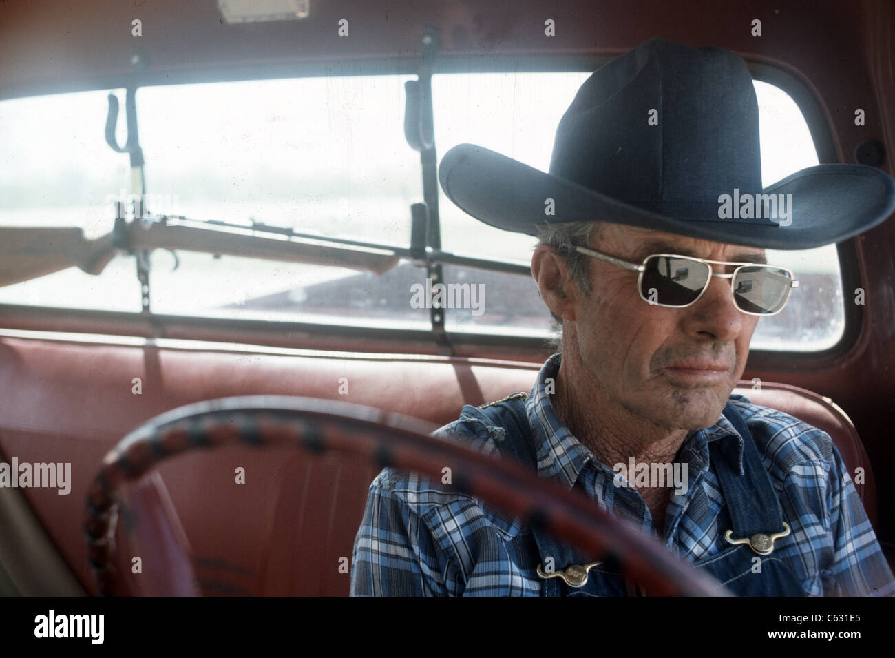Portrait of cowboy portant des lunettes de soleil Ray-ban en salopette  assis en camion avec carabine sur un rack dans la vitre arrière Photo Stock  - Alamy