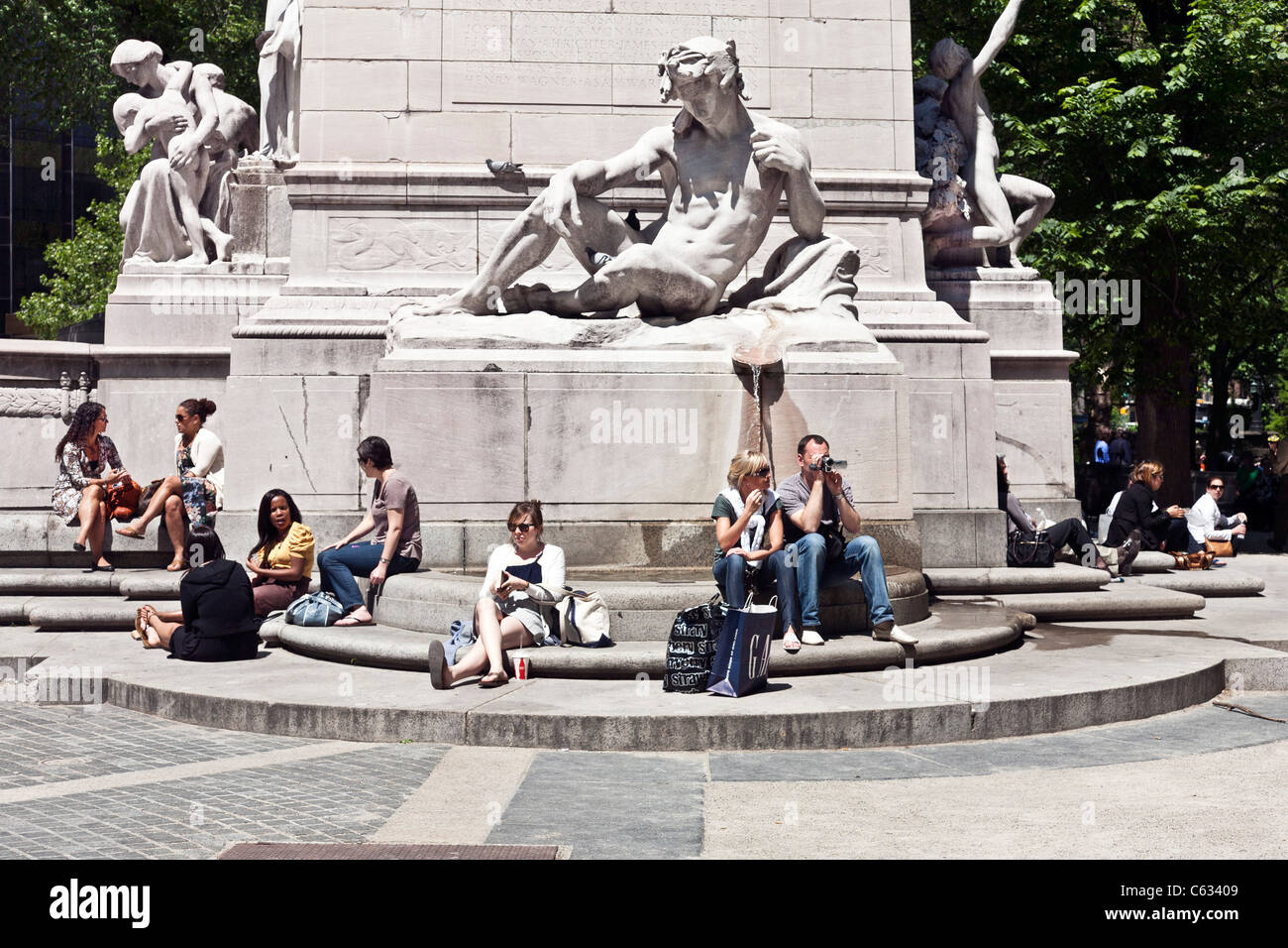 Diverses personnes y compris les touristes et les New-Yorkais se détendre sur les étapes de l'USS Maine monument à l'entrée de Central Park à New York Banque D'Images
