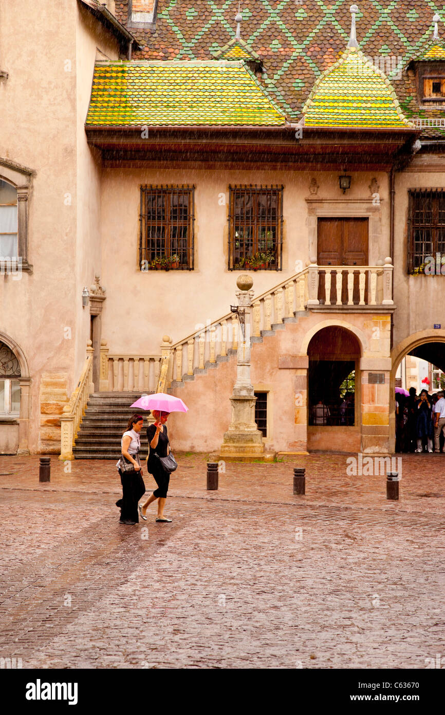 Deux femmes marche sous un parapluie rose dans une tempête de pluie à Colmar, Haut-Rhin Alsace France Banque D'Images