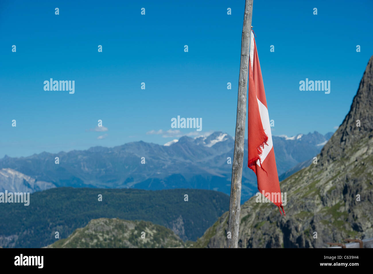 Un drapeau national suisse sur perche à un refuge de montagne au-dessus du barrage d'Emosson en Valais, Suisse. Banque D'Images