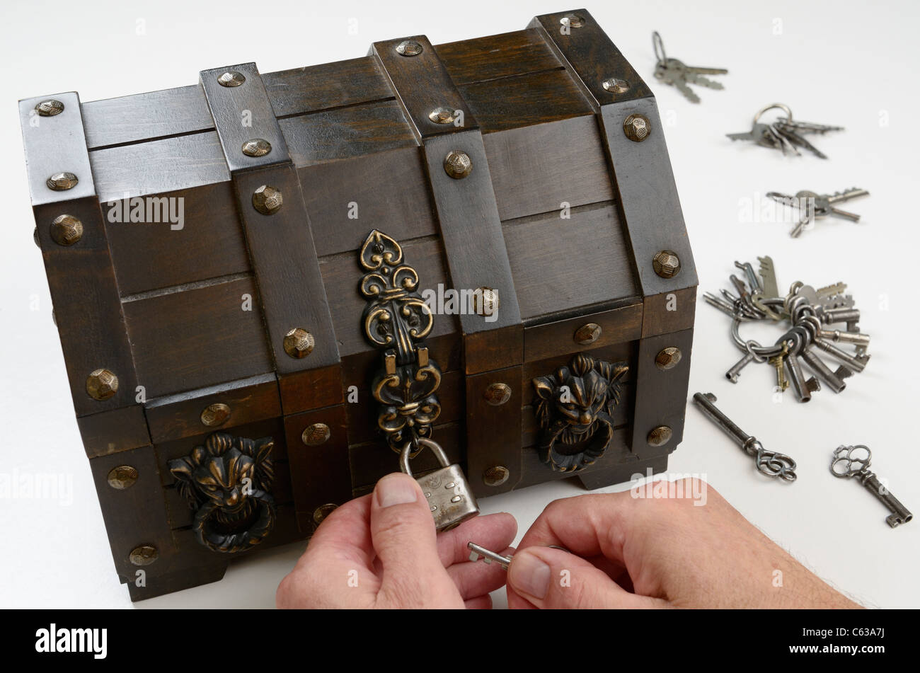 Les mains de l'homme à la recherche de la clé pour mettre en place le verrou sur un coffre de trésor Banque D'Images
