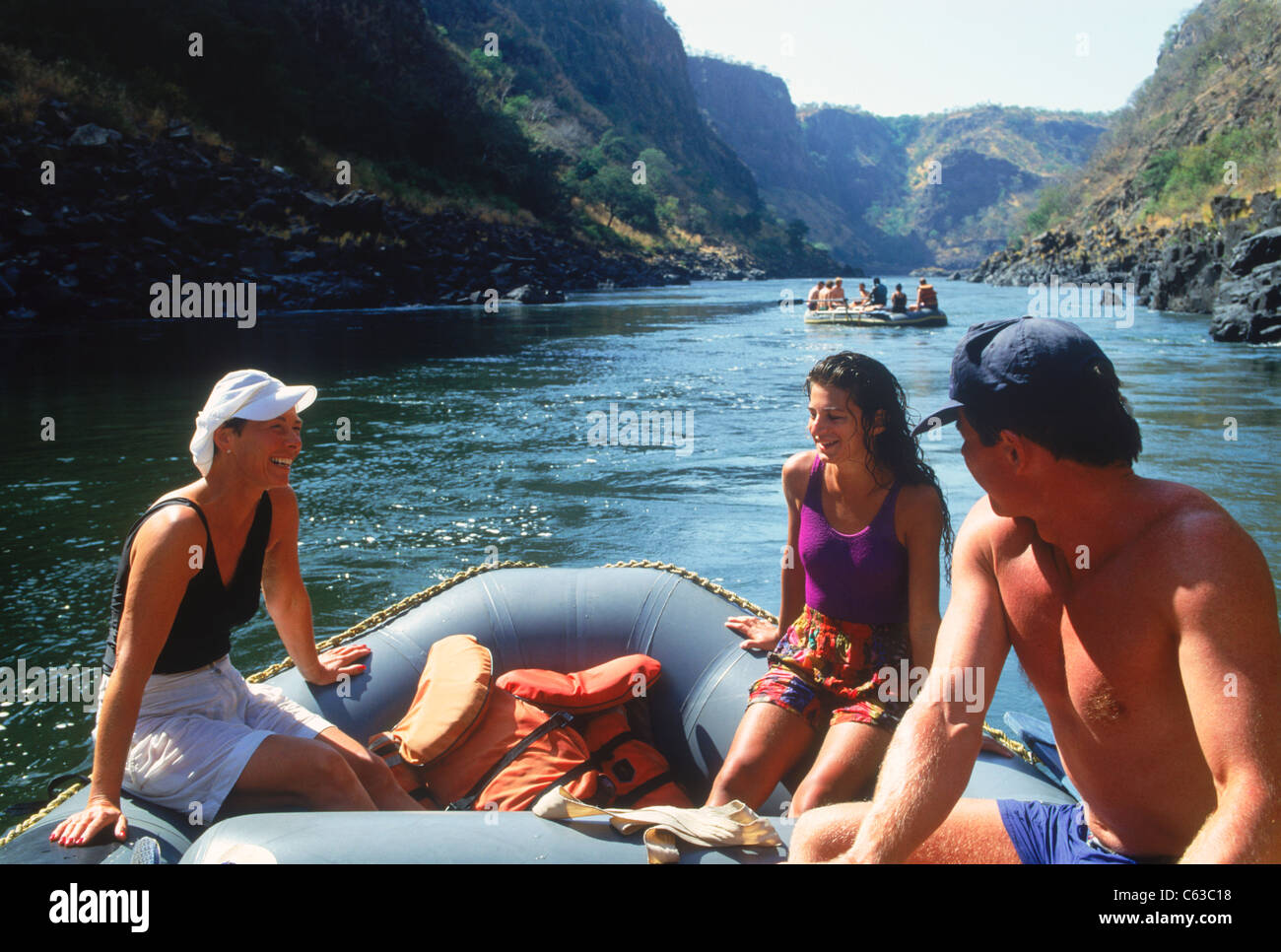 Les touristes et les guides tout en relaxant le rafting sur le fleuve Zambèze entre les rapides et entre la Zambie et le Zimbabwe Banque D'Images