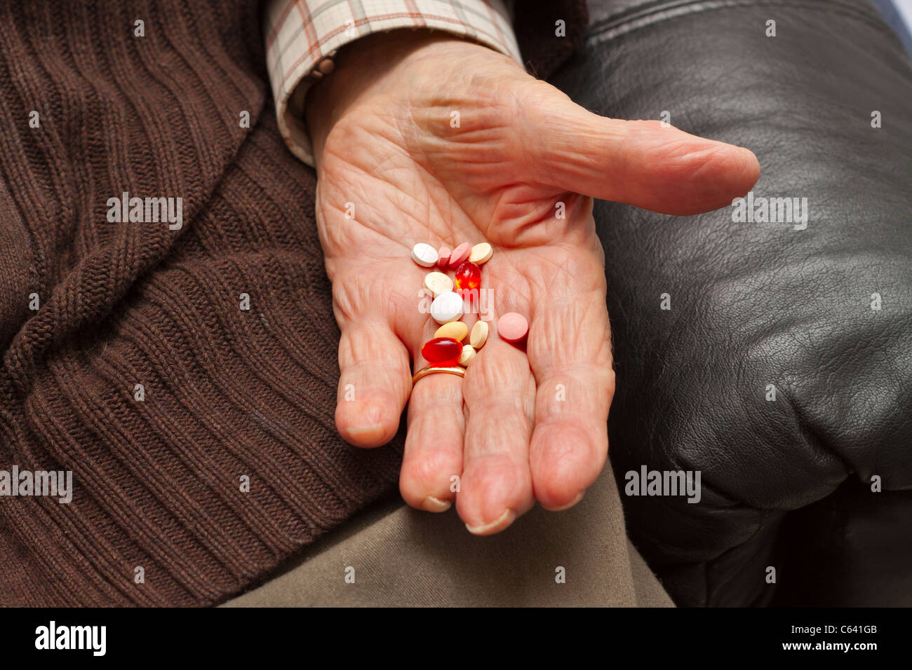 Un homme âgé est titulaire d'une main avec un assortiment de comprimés Banque D'Images