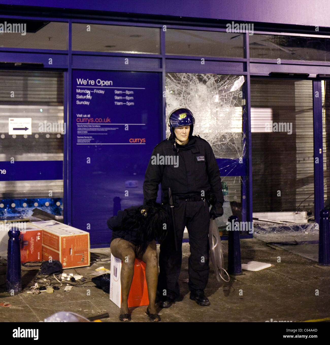Un agent de police guards une femelle pillard à Brixton au cours de l'émeute de Londres 2011. Banque D'Images