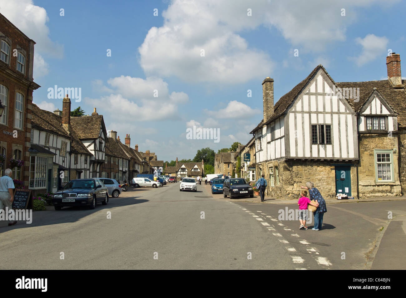 Les touristes profitant de la grande rue historique village de Lacock dans le Wiltshire England UK Banque D'Images