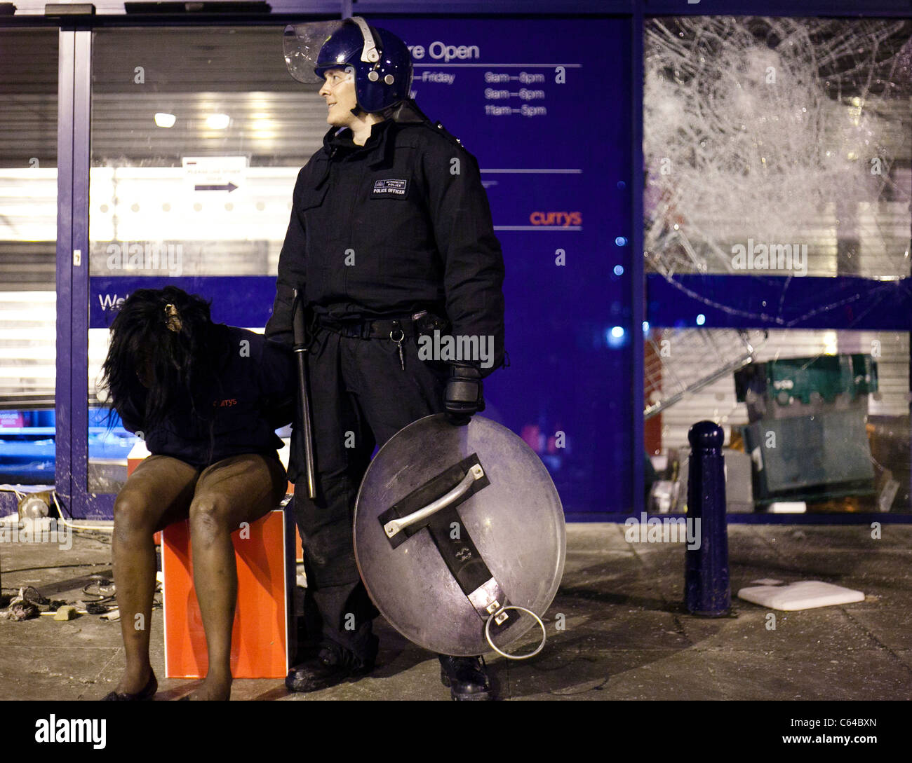 Un agent de police guards une femelle pillard à Brixton au cours de l'émeute de Londres 2011. Banque D'Images