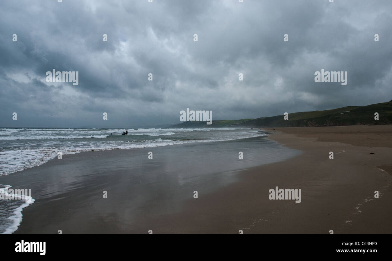 Cornwall, Whitsand Bay sur un jour venteux nuageux - des surfeurs dans l'arrière-plan. Banque D'Images