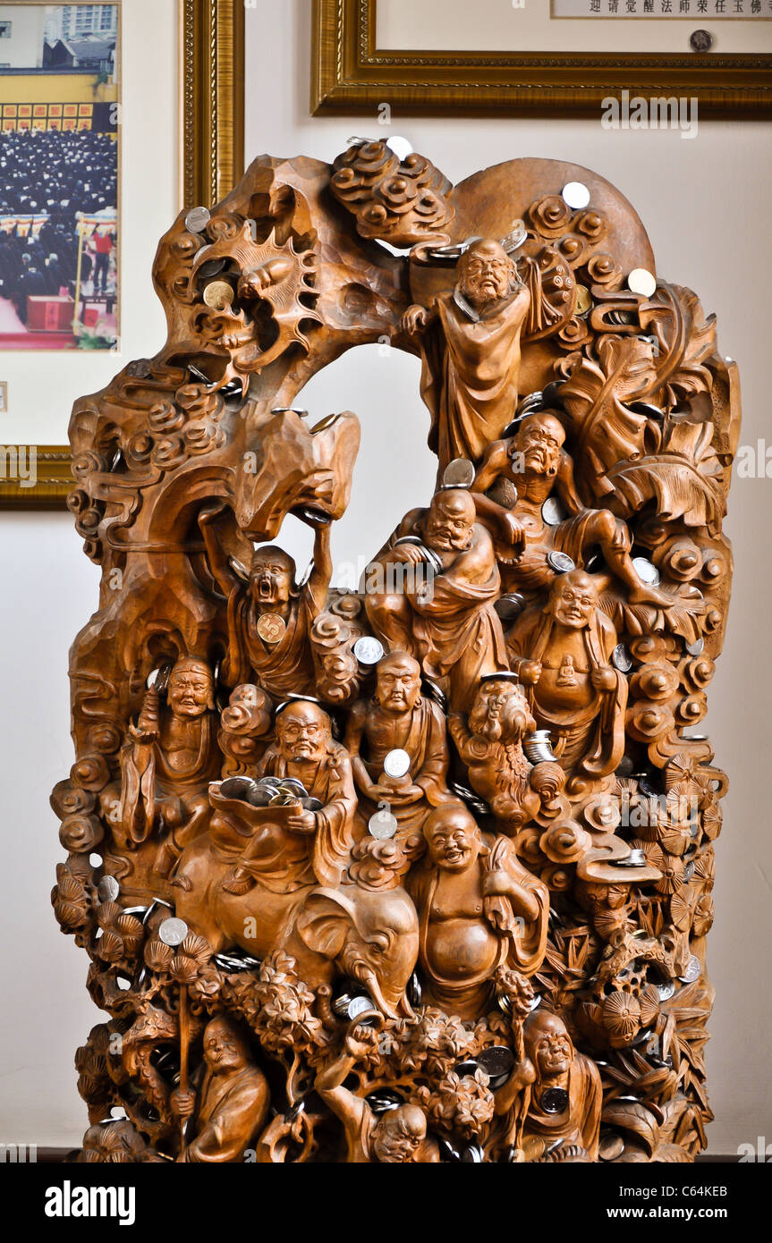 Belle scène en bois sculpté représentant différentes statues de bouddha et d'animaux avec des pièces Banque D'Images