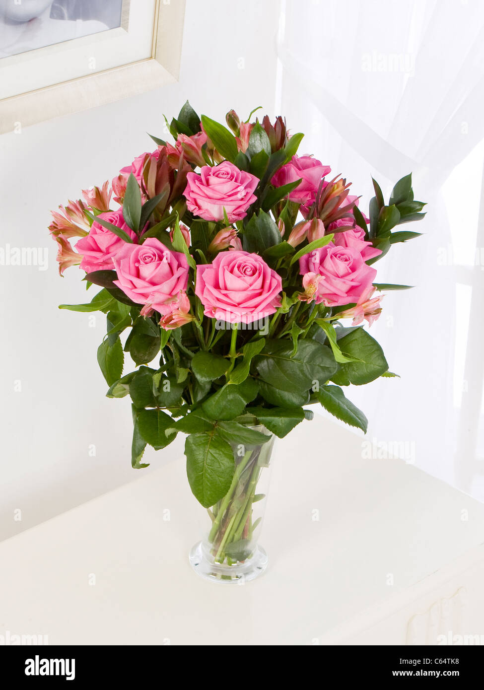 Bouquet de roses roses et de l'Alstroemeria dans un vase par une fenêtre Banque D'Images