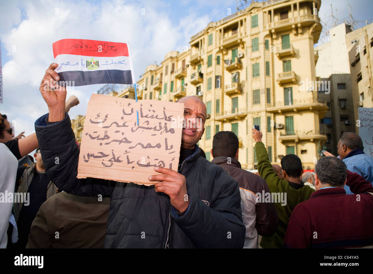 Un homme est titulaire d'un drapeau égyptien et signer lors de la manifestations anti-gouvernementales en place Tahrir au centre du Caire le 31 janvier 2011 Banque D'Images
