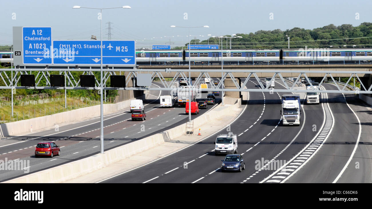 Infrastructure de transport pont ferroviaire et trains de voyageurs traversant la circulation routière à la sortie 28 M25 autoroute Brentwood Essex Angleterre Royaume-Uni Banque D'Images