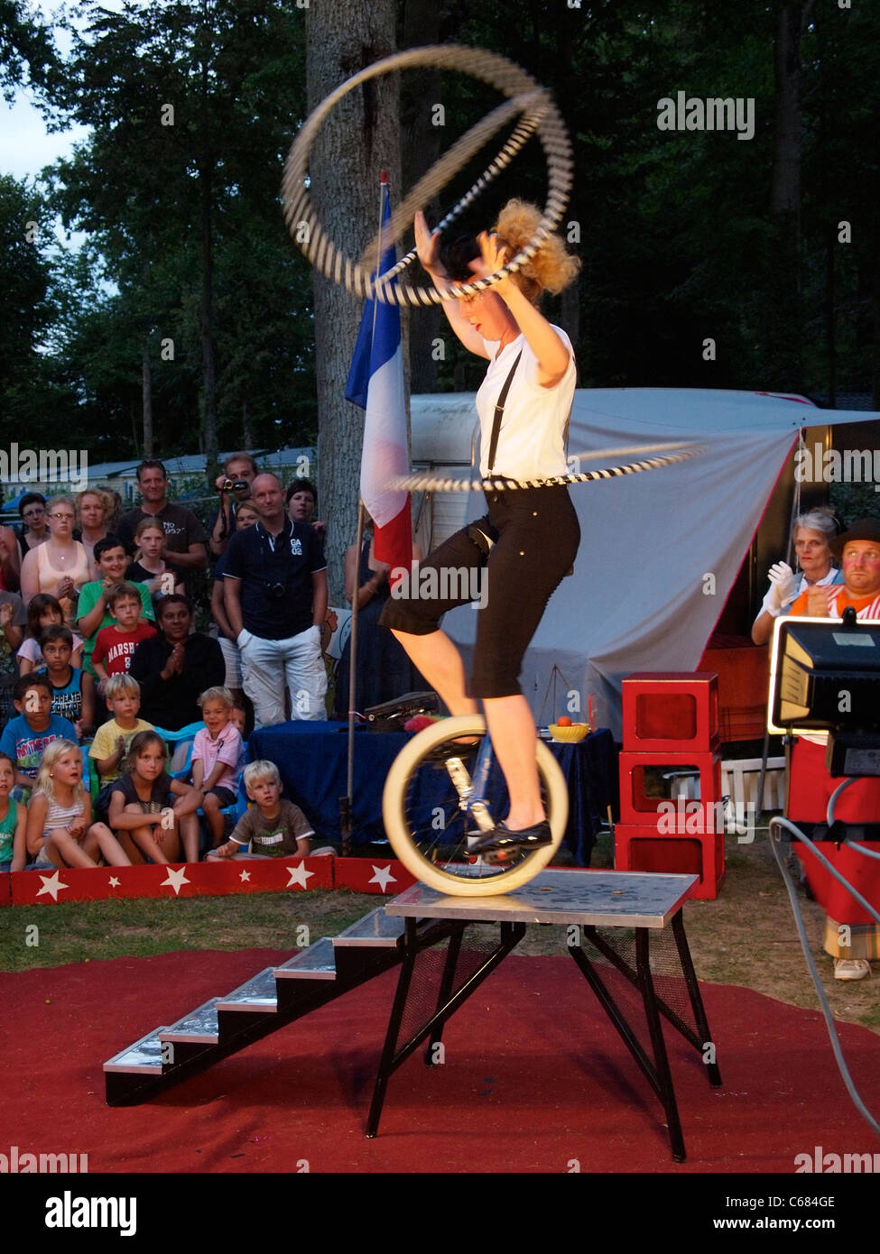 Acrobat féminine sur unicycle dans un petit cirque en plein air, d'effectuer sur un site de camping en Mer, France Banque D'Images