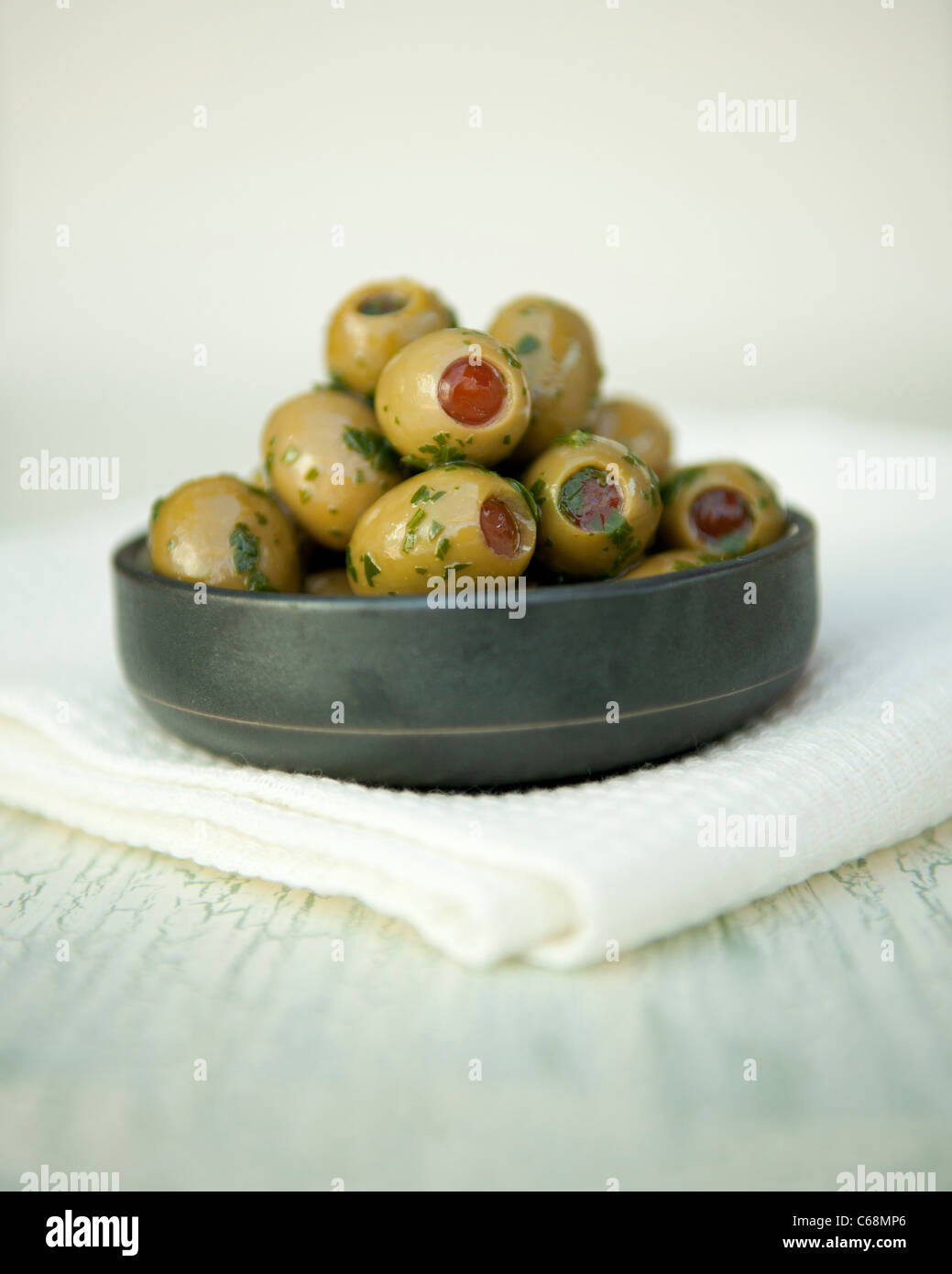 Olives vertes farcies aux poivrons rouges à l'huile d'olive et les herbes dans un pot Banque D'Images