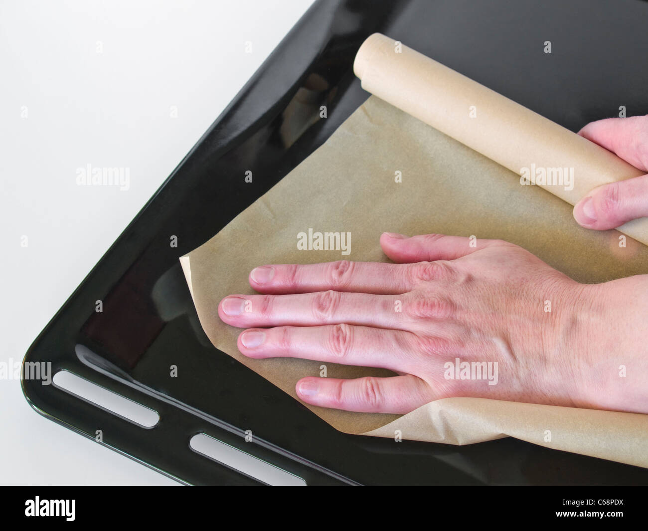 Auf ein Backblech Backpapier gelegt wird | Une personne mettre un peu de papier cuisson sur une plaque à pâtisserie Banque D'Images