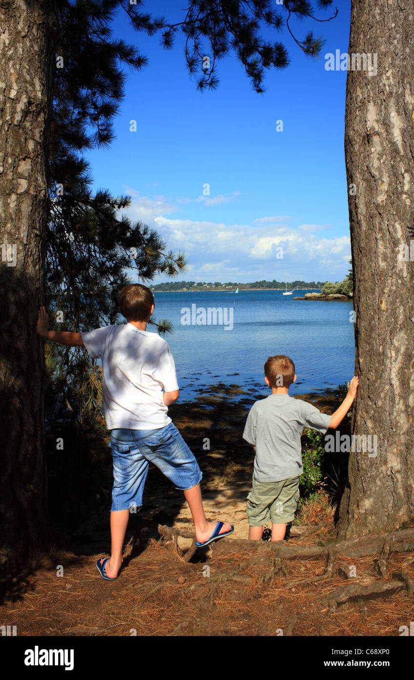 Les garçons à la vue d'au Golfe du Morbihan et de l'Ille aux moines de l'Ile de Berder, Larmor-Baden, Morbihan, Bretagne, France Banque D'Images