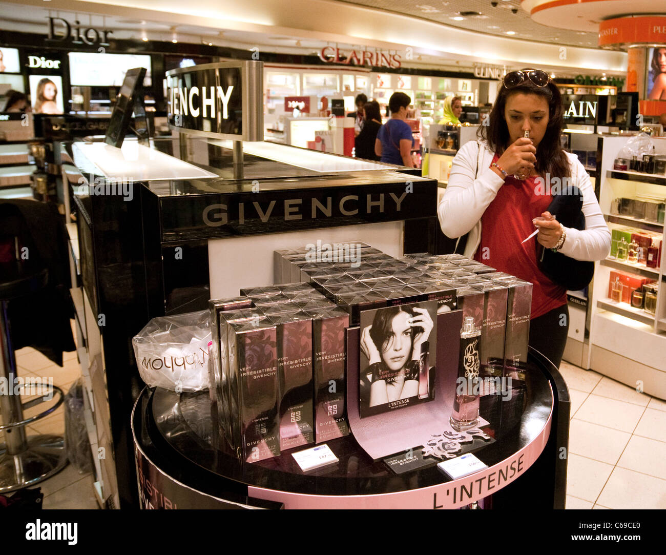 Une adolescente essayant Givenchy parfum, la boutique hors taxes, Terminal 3 de l'aéroport Heathrow de Londres, UK Banque D'Images