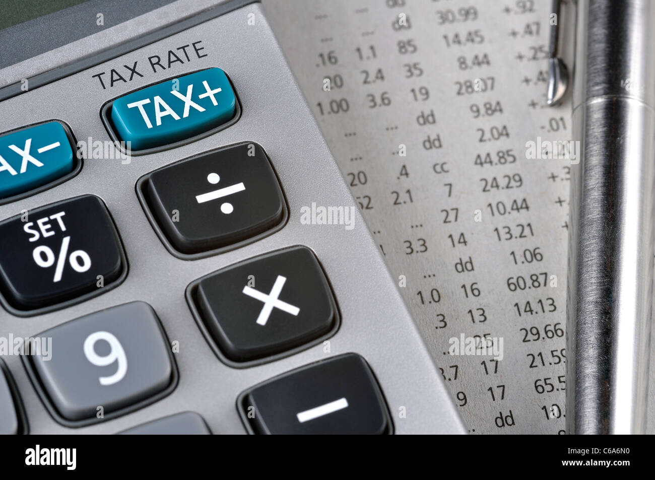 Détail de calculatrice, se concentrant la touche TAX, à côté d'une feuille de papier avec des chiffres et un stylo en métal. Banque D'Images