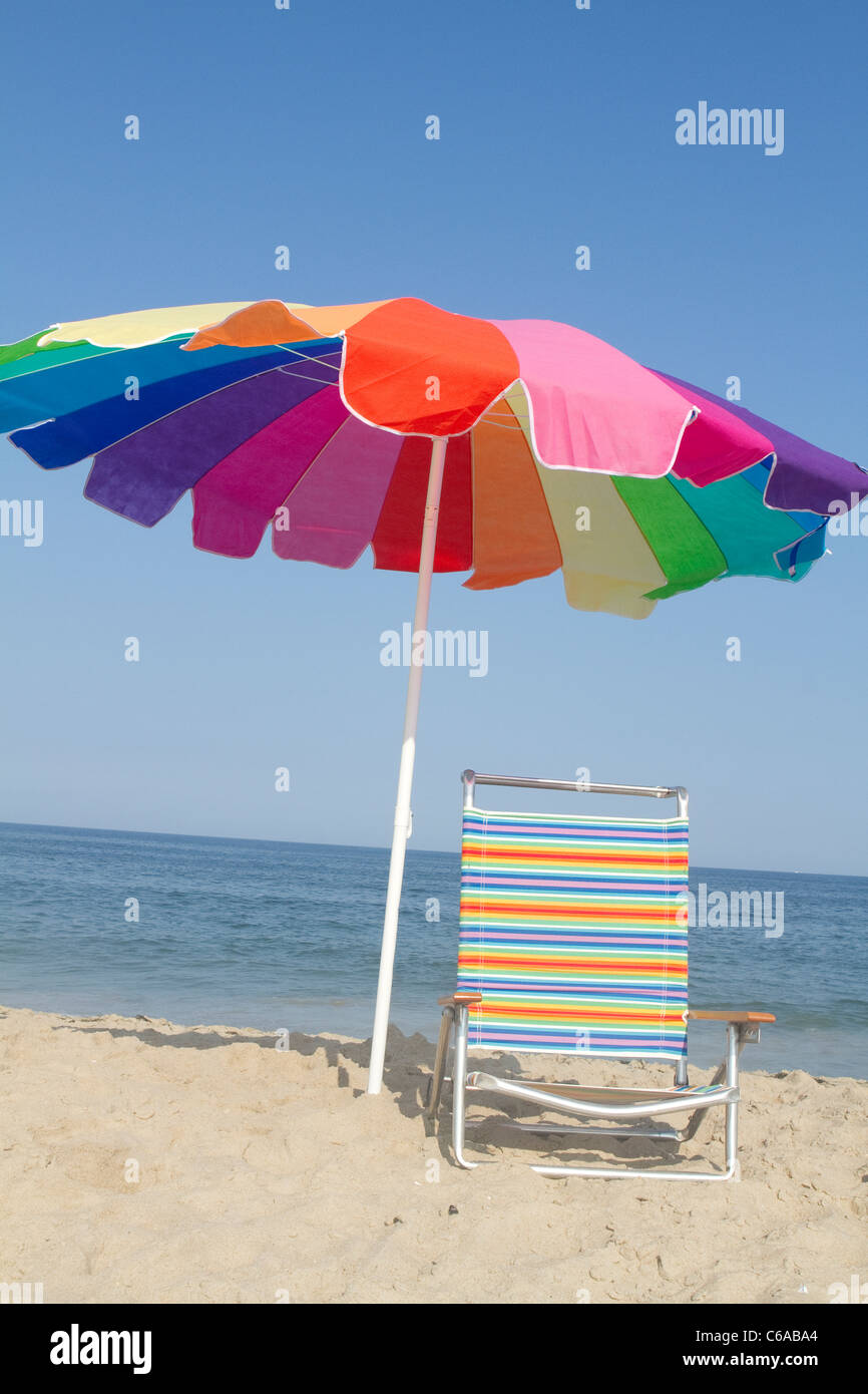 Une couleur arc-en-ciel parapluie et chaise de plage correspondant sur la plage. Banque D'Images