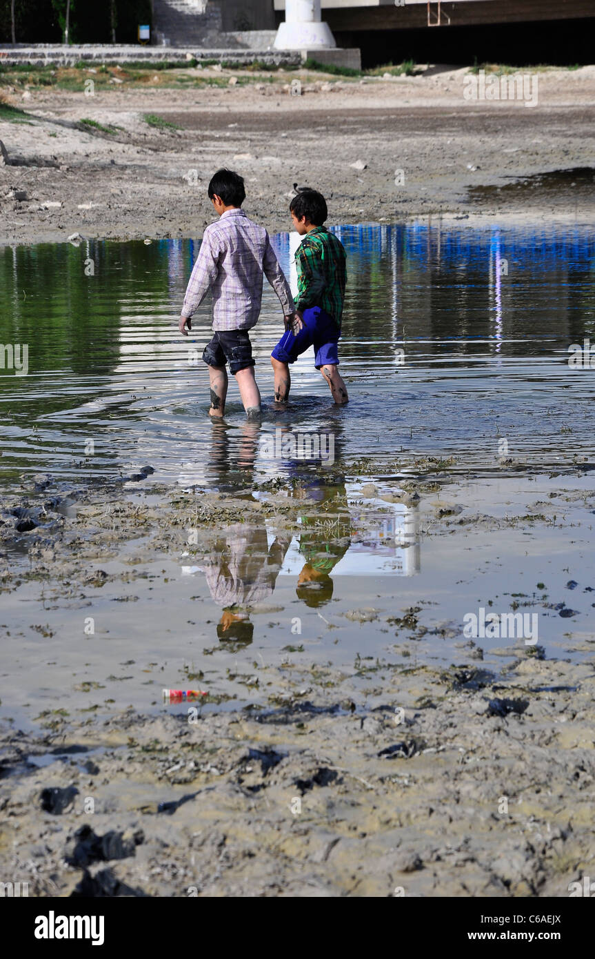 Deux frères marcher dans l'eau restante de la rivière Zayanderud à Ispahan en Iran. Banque D'Images
