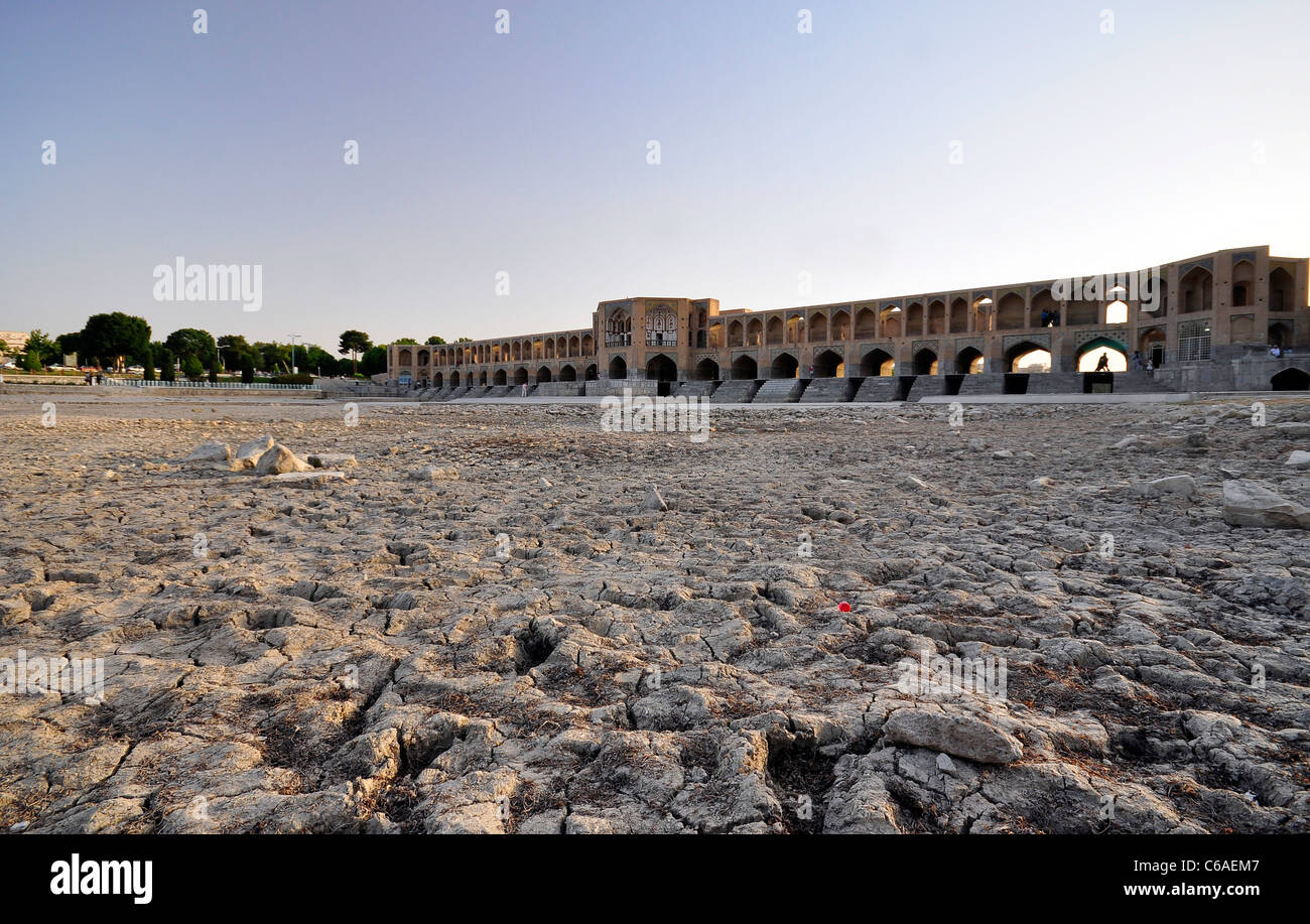 Le lit de la rivière Zayandeh fissuré à cause de la rivière sever la sécheresse et pont Khaju en arrière-plan à Isfahan, Iran. Banque D'Images