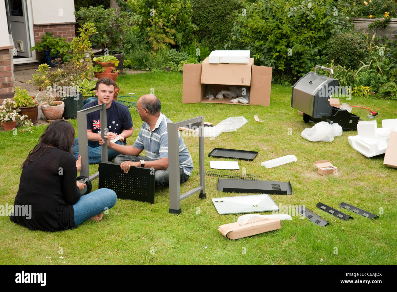 Les gens de l'assemblage d'un barbecue pré emballées dans leur jardin, UK Banque D'Images