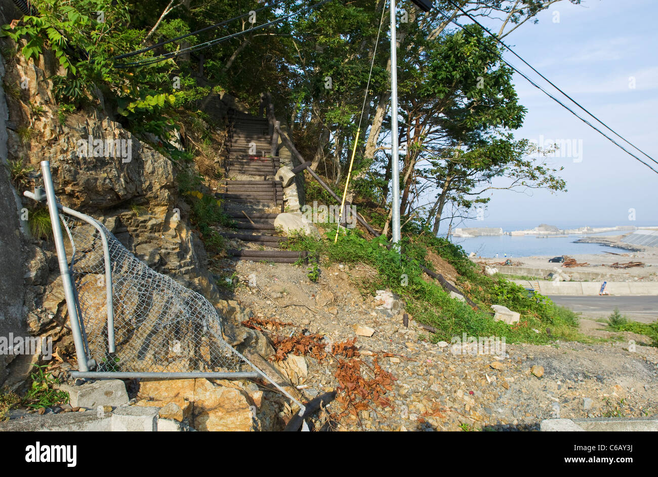 Escaliers, garde-corps et clôture sur le flanc d'une montagne, montrant les dommages causés par un tsunami Banque D'Images