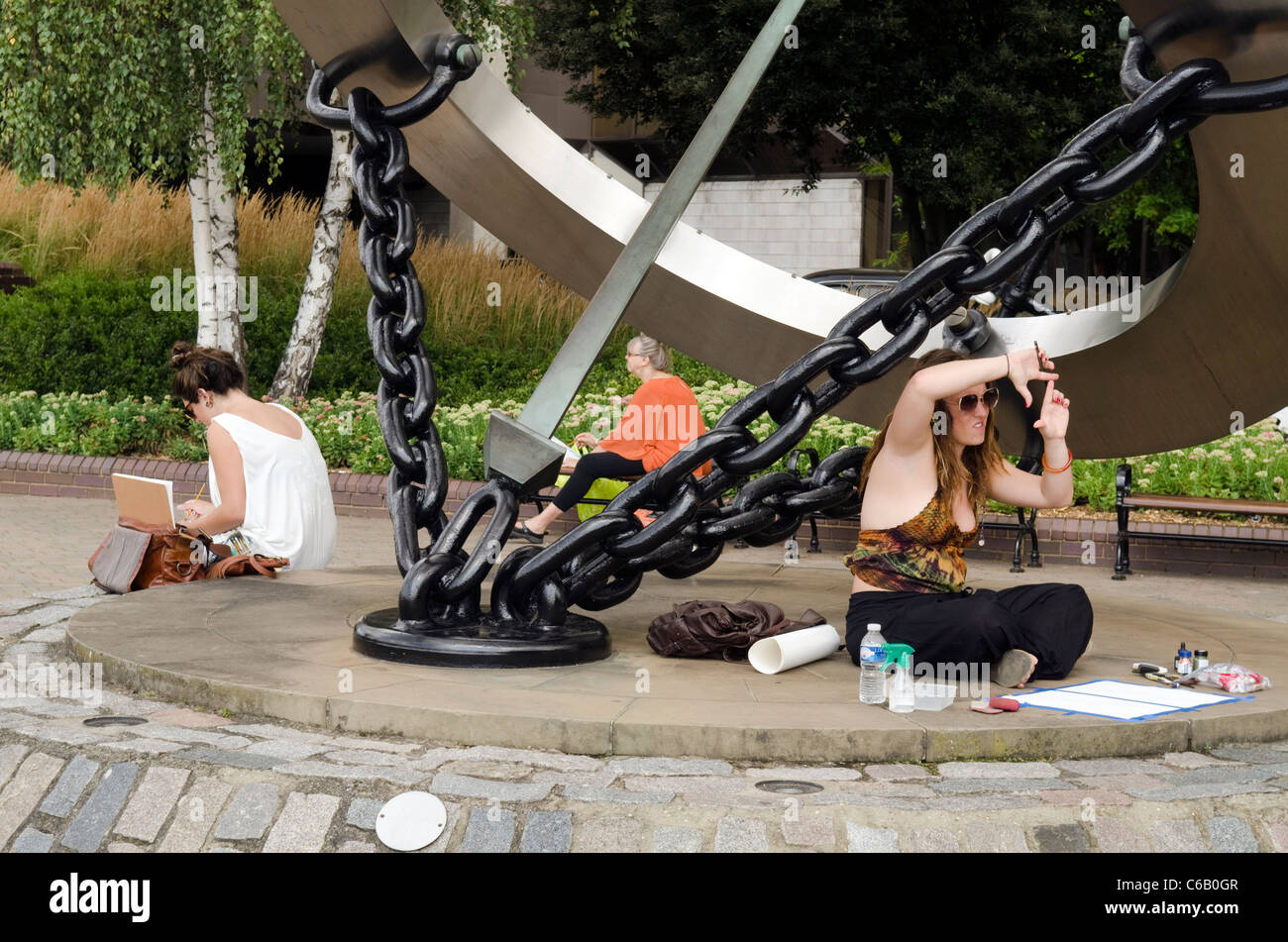 Trois photos de la peinture de l'artiste féminine Londres assis en dessous de la sculpture montre sur les rives de la Tamise. Banque D'Images