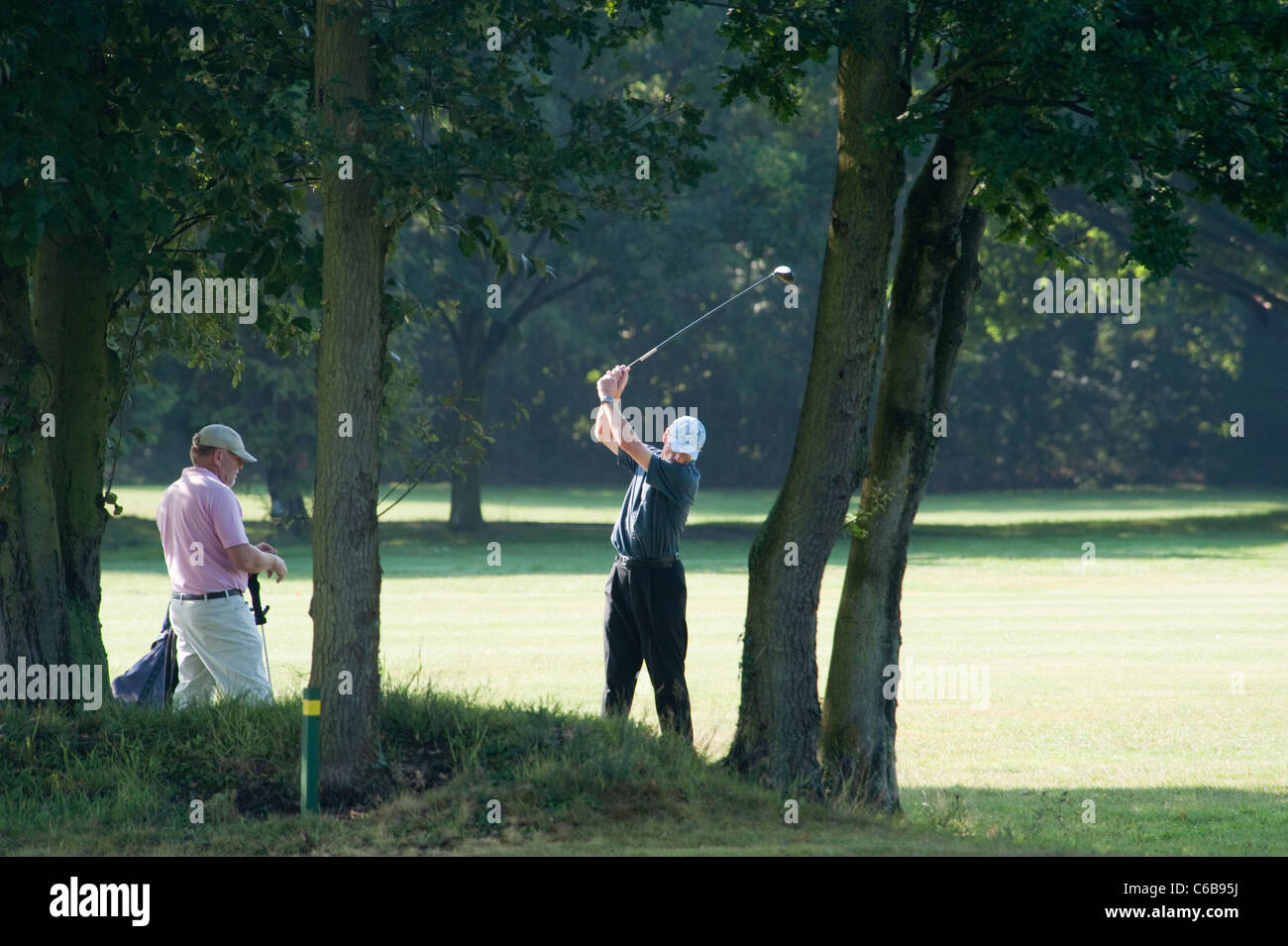 Deux hommes des golfeurs sur le green la rotation un bois et pris le départ sur une journée ensoleillée à Stanmore golf course Banque D'Images