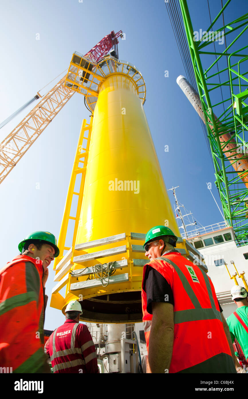 Une grue soulève un morceau de transition sur le pont d'une péniche, prêt à sortir à l'éolien offshore Walney Banque D'Images