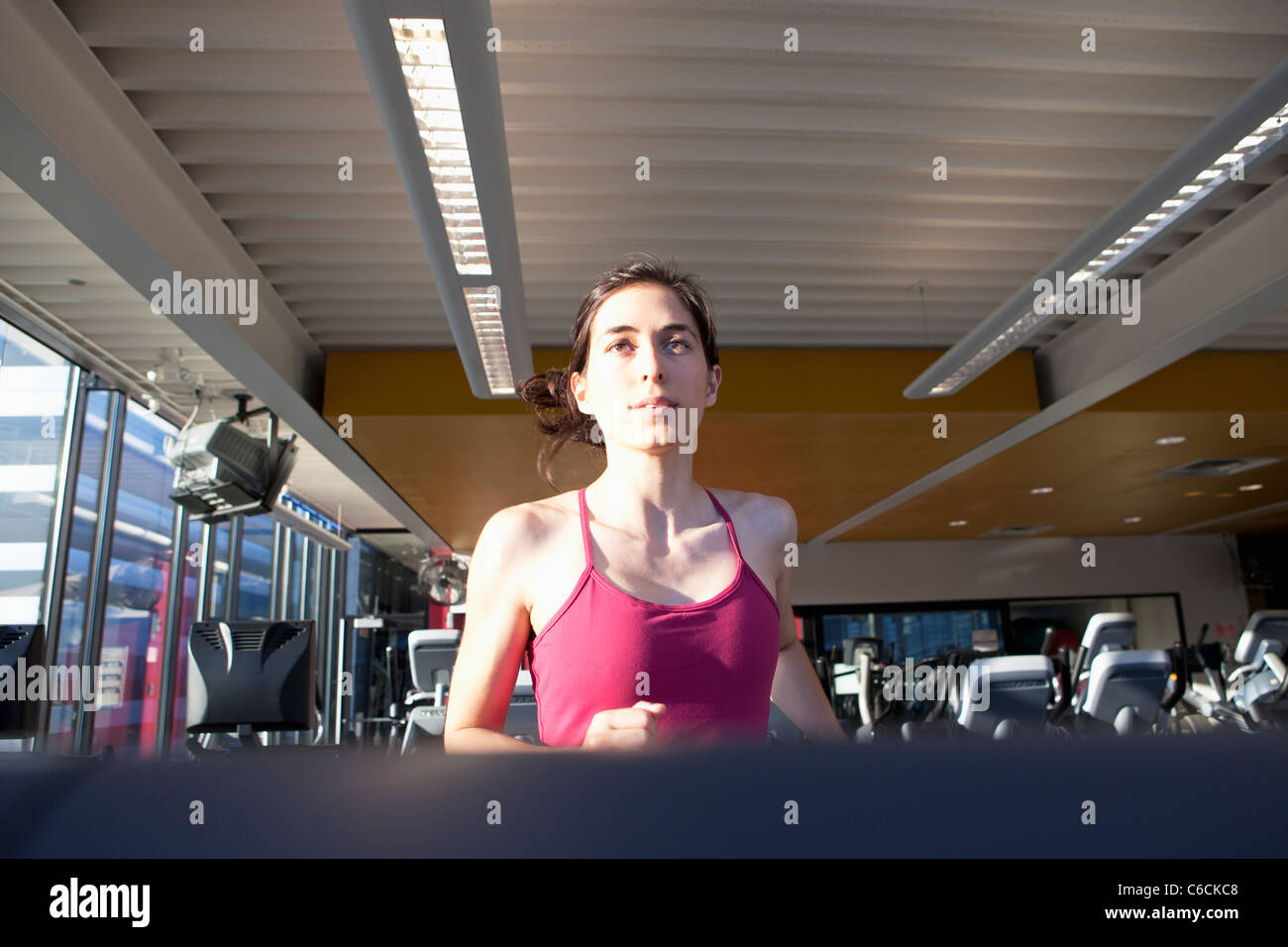 Femme d'exécution sur un tapis roulant dans un club de santé Banque D'Images
