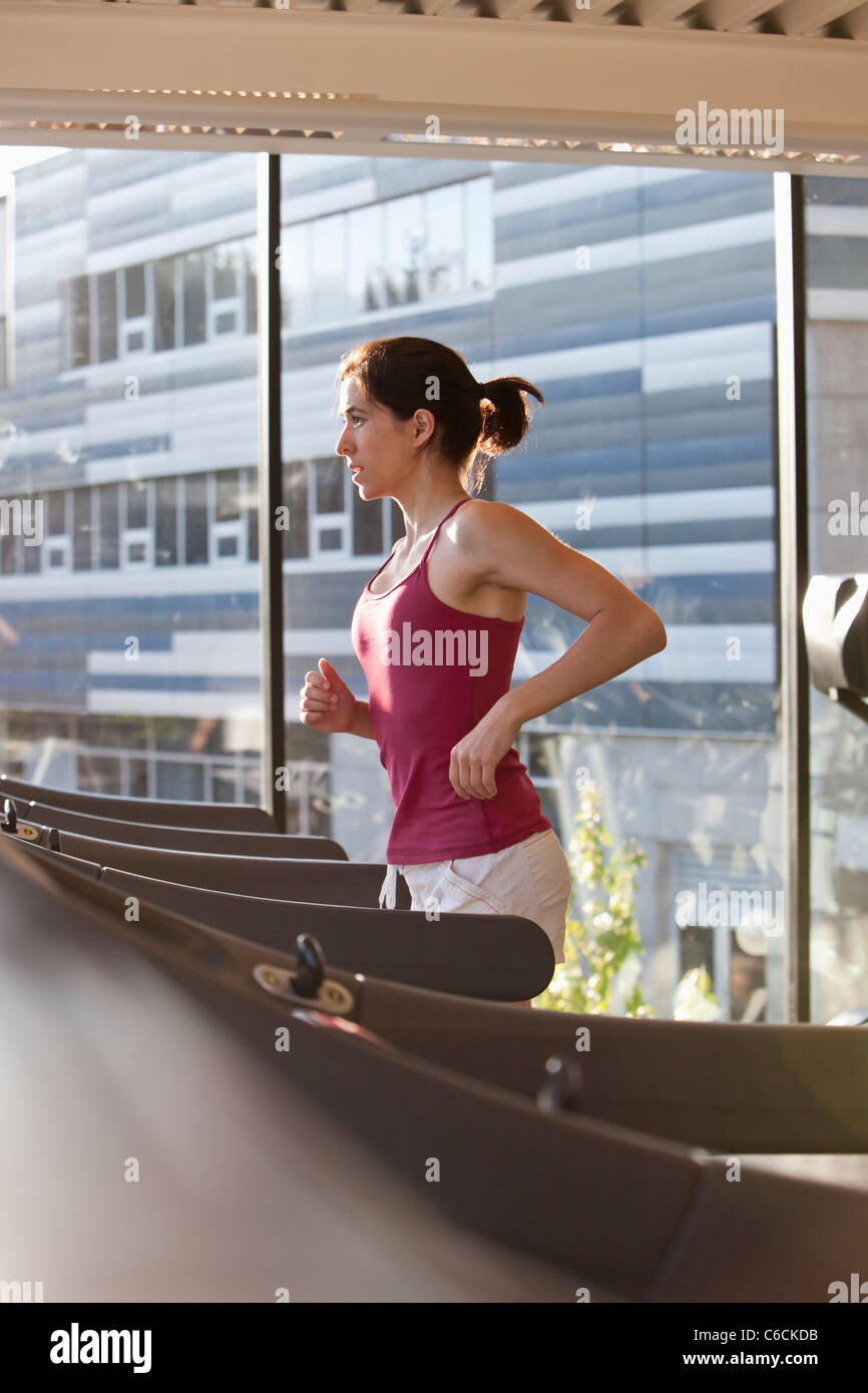 Femme d'exécution sur un tapis roulant dans un club de santé Banque D'Images