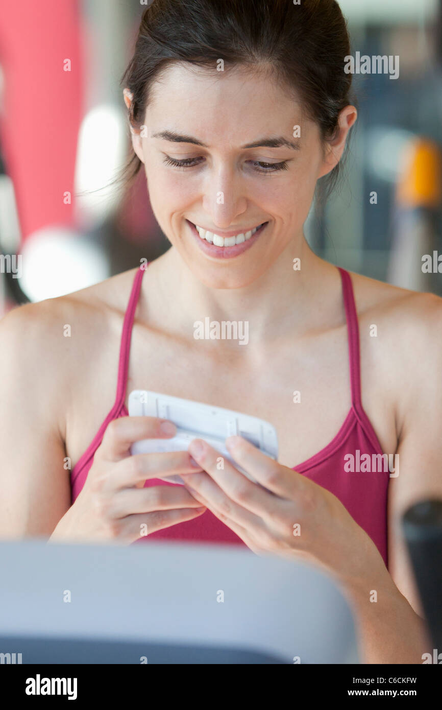 Femme sur tapis roulant text messaging on cell phone Banque D'Images
