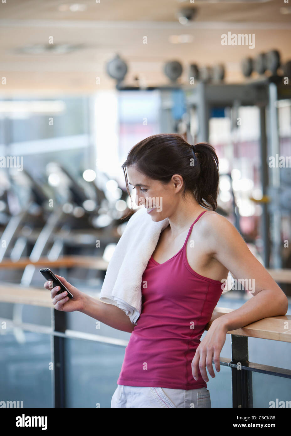 Woman text messaging on cell phone in health club Banque D'Images