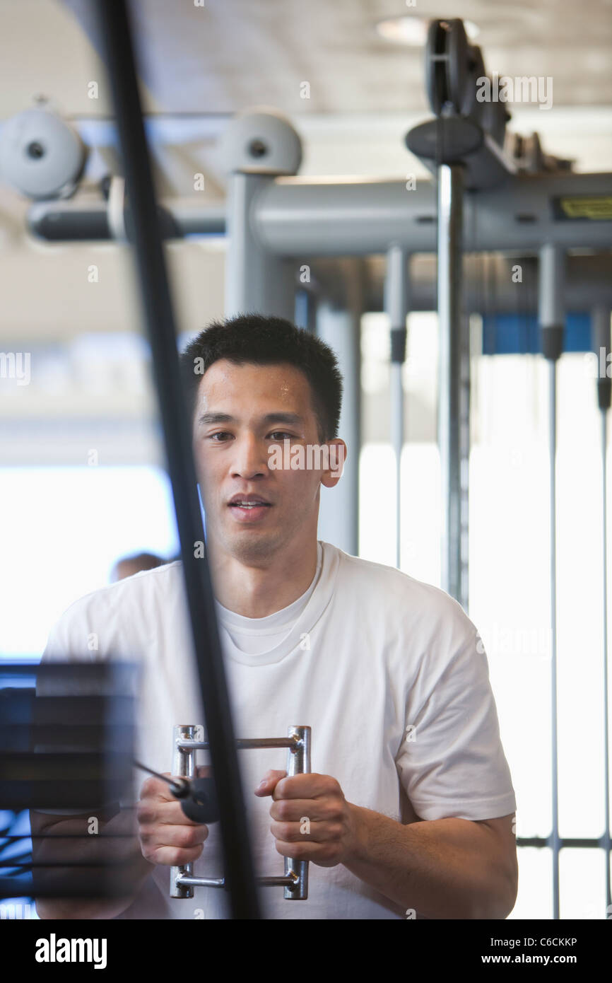 Chinese man lifting weights in health club Banque D'Images