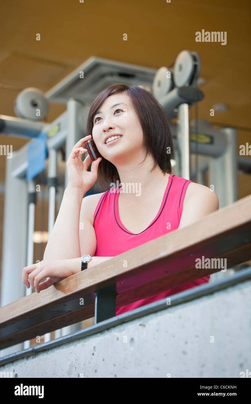 Korean Woman talking on cell phone in health club Banque D'Images