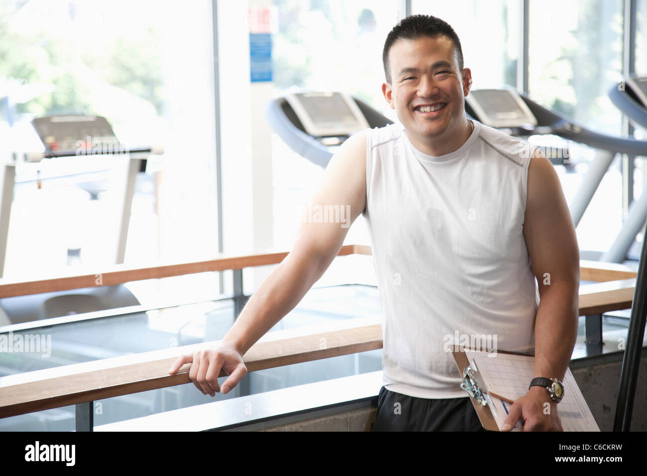 Smiling man with clipboard standing in health club Banque D'Images