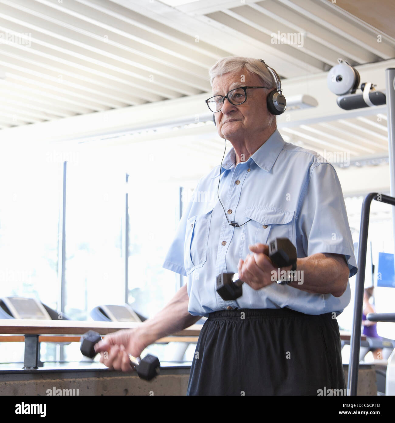 Senior man lifting weights in health club Banque D'Images