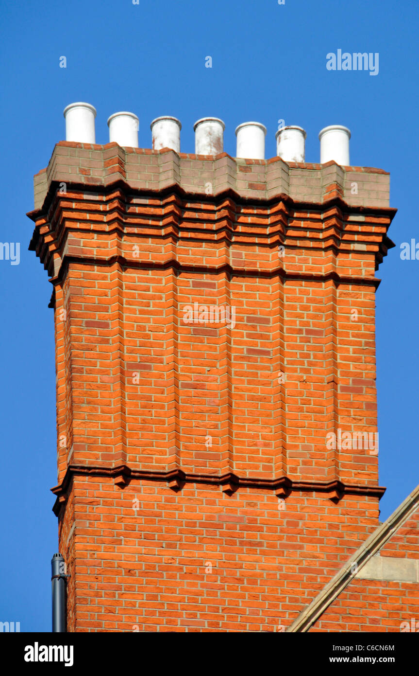 Close up of cluster en brique rouge construit corbeled cheminées cheminées & pots de cheminée au-dessus du niveau du toit bleu du ciel jour London England UK Banque D'Images