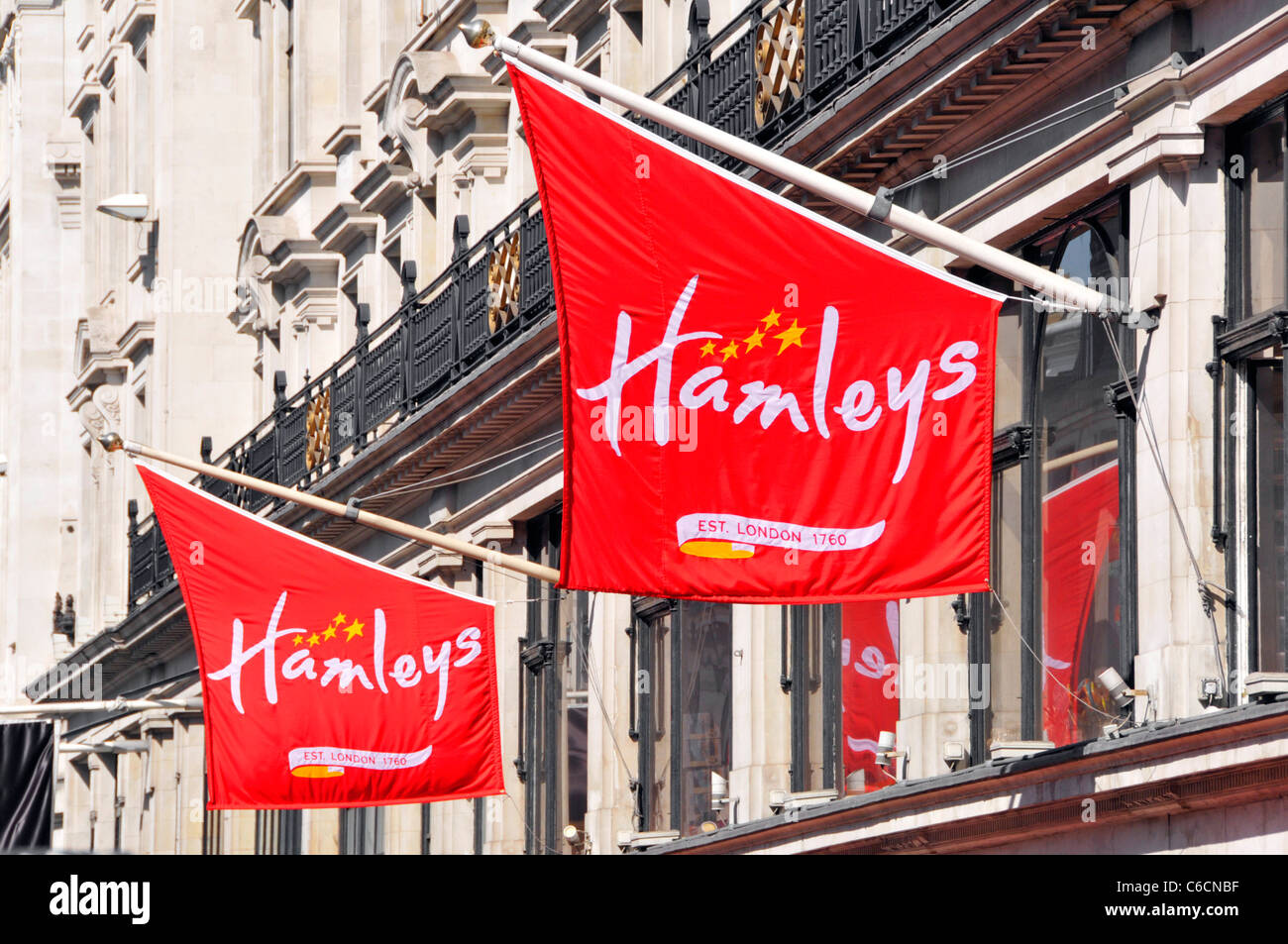 Logo Hamleys sur des bannières rouges au-dessus de la célèbre boutique de jouets phare de magasin à Londres West End emplacement commercial à Regents Street Angleterre Royaume-Uni Banque D'Images