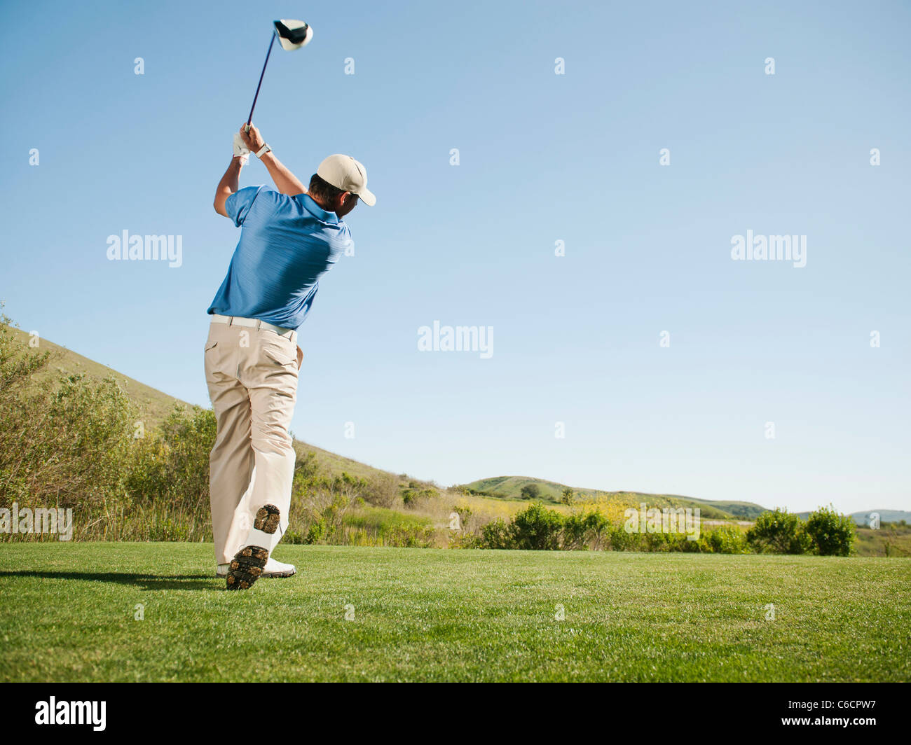 Caucasian golfer swinging golf club Banque D'Images