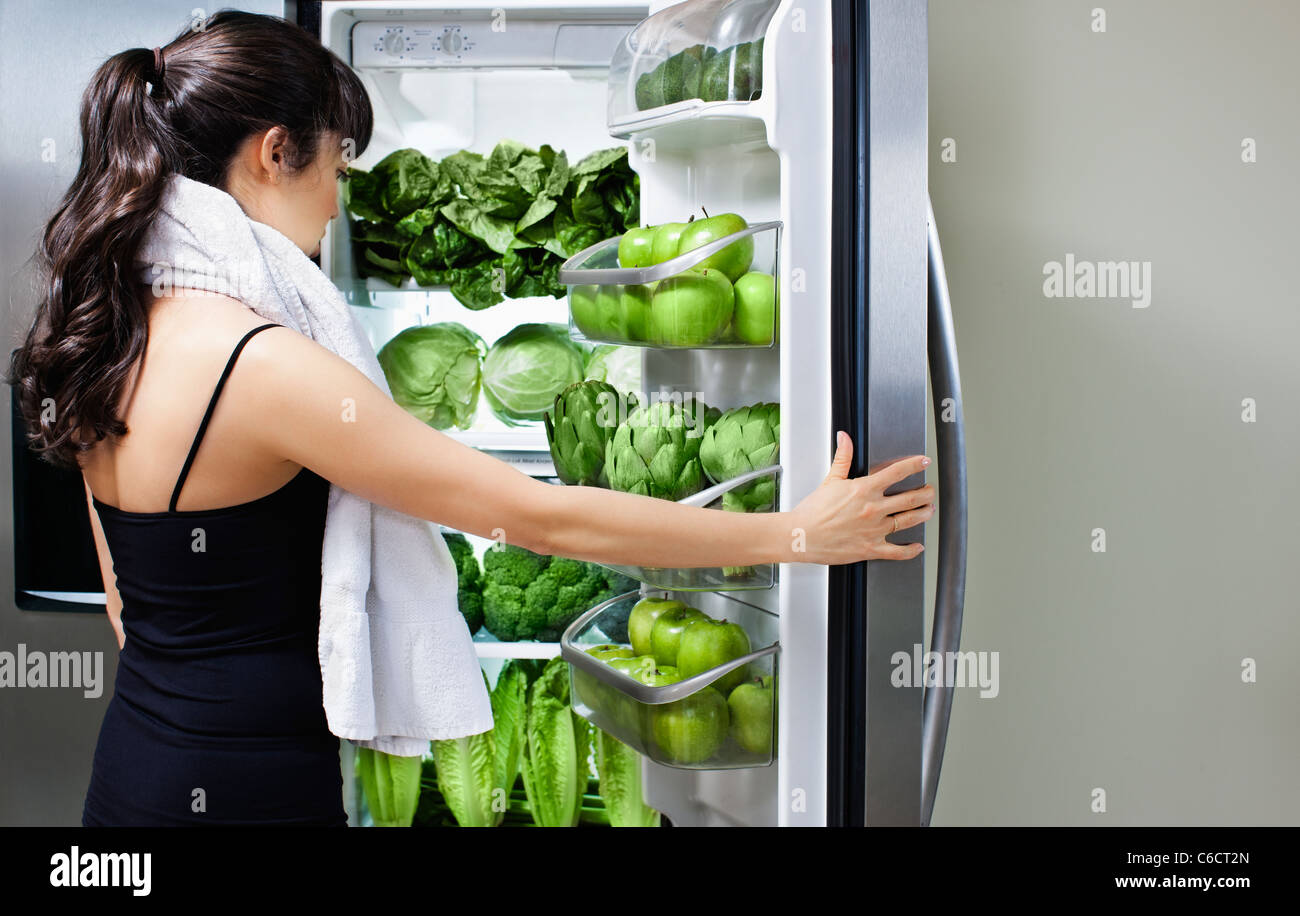 Mixed Race woman looking at légumes verts dans réfrigérateur Banque D'Images Mixed Race woman looking at légumes verts dans réfrigérateur Banque D'Images