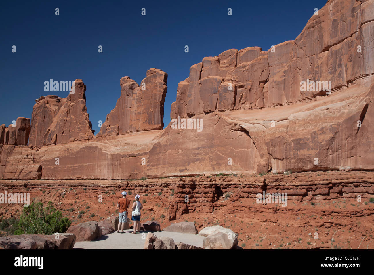 Moab, Utah - un couple se penche sur l'un des murs qui composent "Park Avenue' dans Arches National Park. Banque D'Images