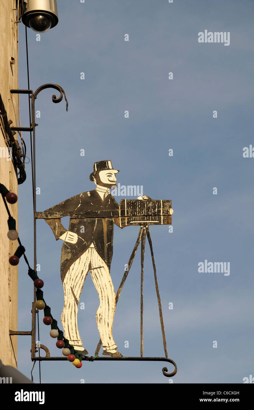 Logo Metal sign advertising Photographer's business Rue St Florent avec Orange France haut de l'appareil photo et le trépied photographe casquette Banque D'Images