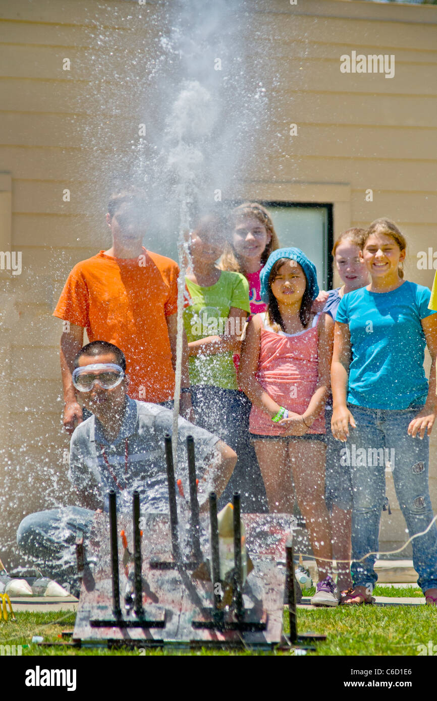 Les élèves adolescents regarder comme un enseignant lance un air-et-eau-powered 'bottle rocket' en été, pour un programme d'apprentissage en classe de science Banque D'Images