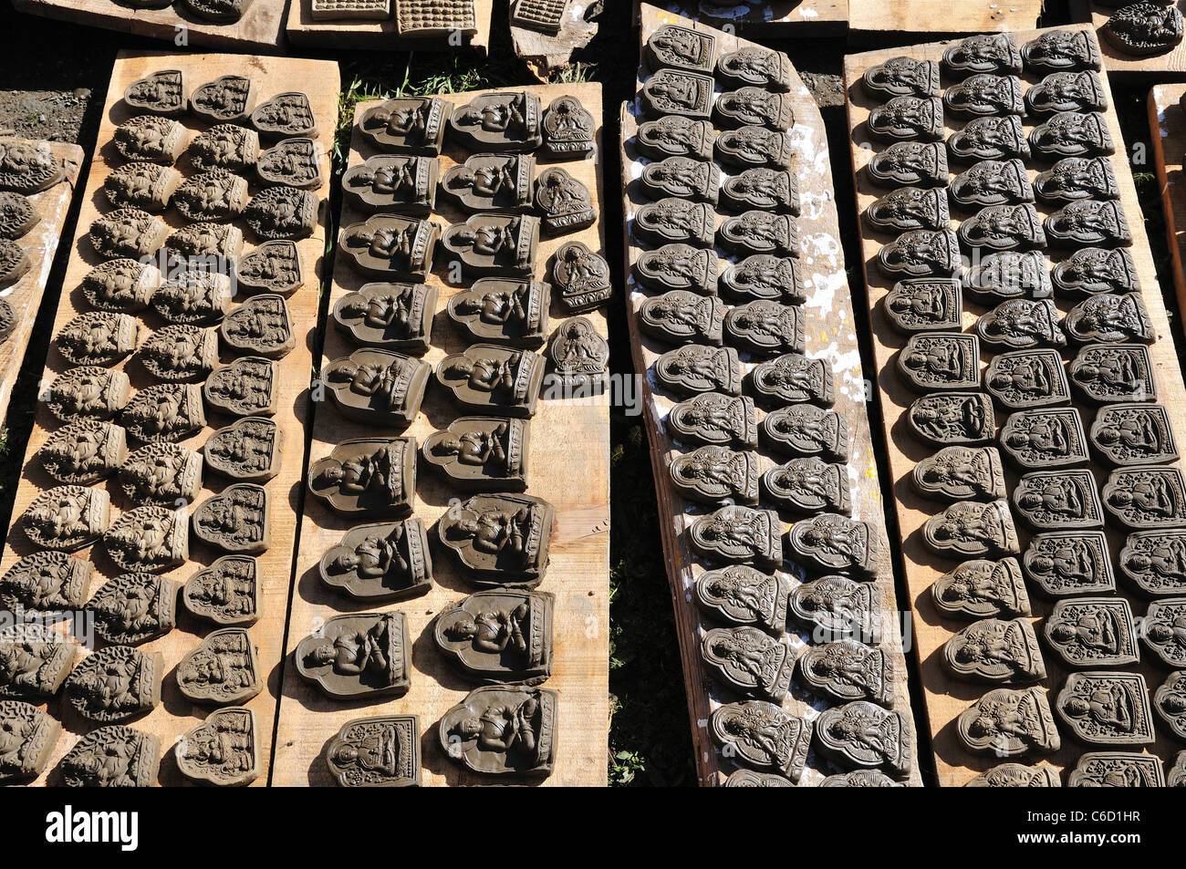 L'argile à la main offrant des comprimés avec figures de Bouddha couché sec en soleil. Au Sichuan, en Chine. Banque D'Images