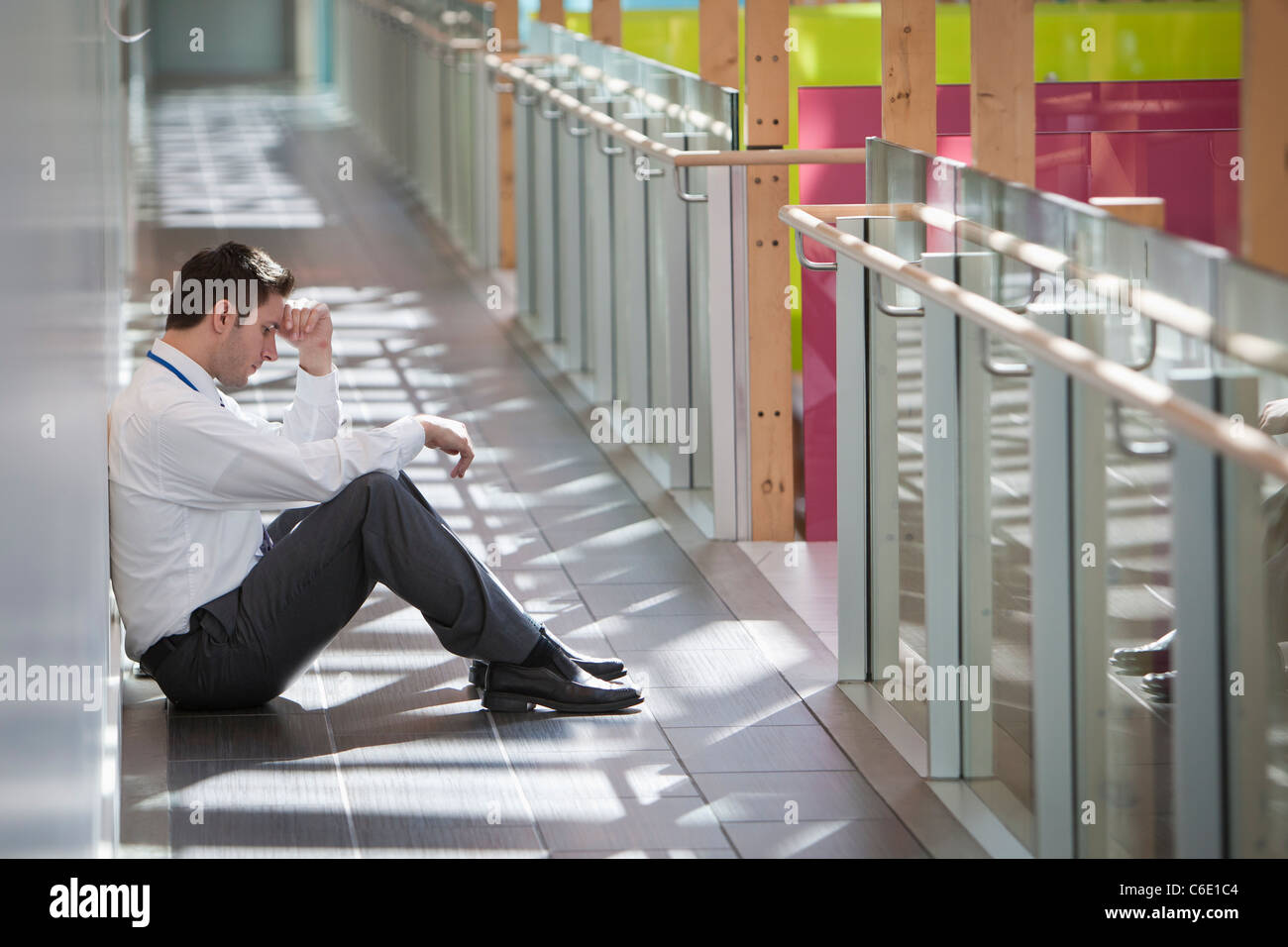 Frustrés businessman sitting on floor office corridor Banque D'Images
