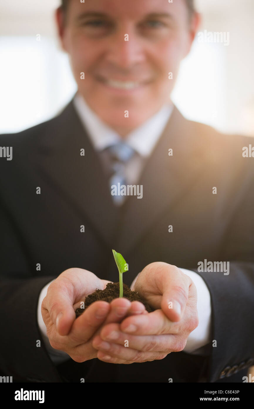 USA, New Jersey, Jersey City, Businessman holding seedling Banque D'Images