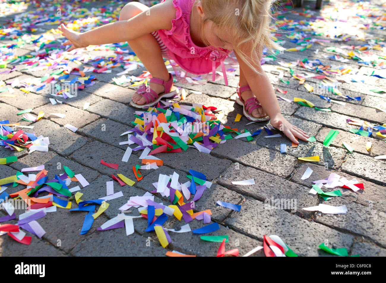 Une jeune fille joue dans les confettis jonchant le sol à la suite d'une cérémonie de lancement du festival à Rogers, Arkansas. Banque D'Images