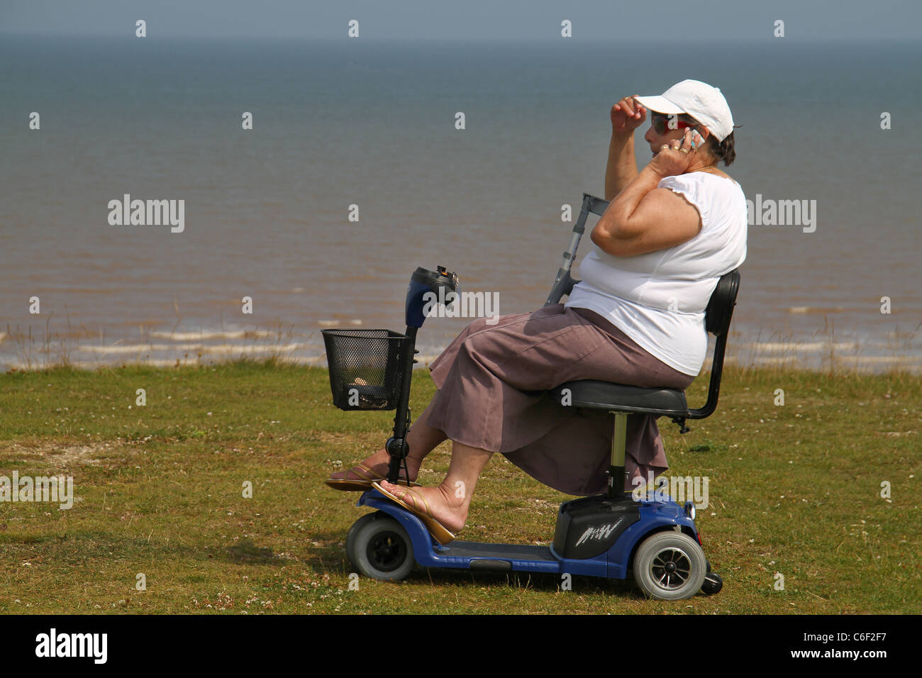Dame en fauteuil roulant motorisé avec téléphone mobile. Banque D'Images
